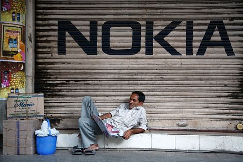 man-reading-a-newspaper-beneath-nokia-logo-in-kolkata-india-m